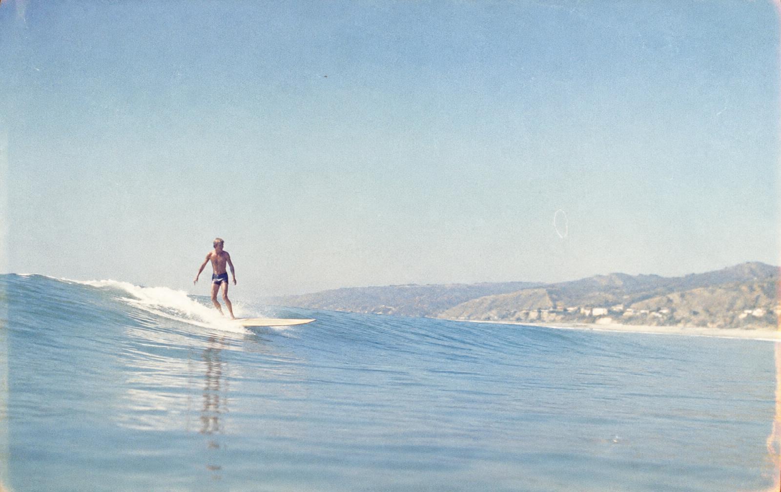 Longboard surfer trimming a glassy wave off Malibu